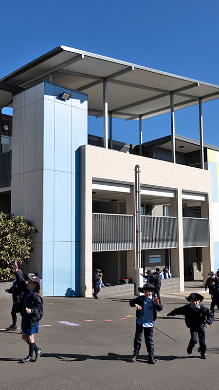 Photo of students on the play groud. They are playing in front of modern school architecture at St Michael's Primary, Baulkham Hills
