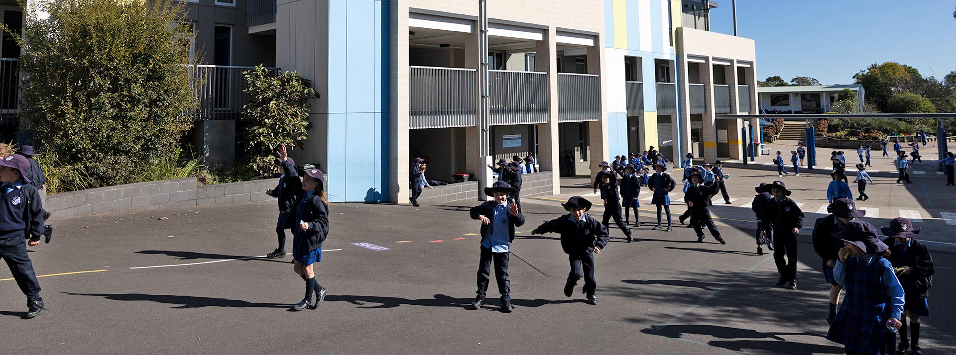 Photo of students on the play groud. They are playing in front of modern school architecture at St Michael's Primary, Baulkham Hills